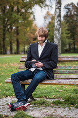 Fototapeta premium Hipster man is reading on a tablet outside