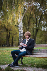 Fototapeta premium Business man is sitting in the park and is writing.