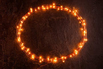 Oval frame of Christmas lights on the black textured wall