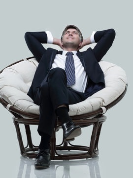 Dreaming businessman is resting, sitting in a large soft chair.