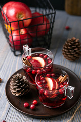 Obraz na płótnie Canvas Mulled wine in glasses on a wooden background. Apples, cranberries, cinnamon, star anise, walnuts, cones