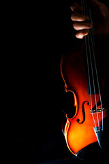 Fototapeta premium Female hand holding violin on a black background, isolated