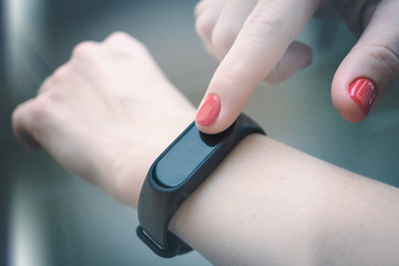 woman uses a fitness bracelet. artistic toning. selective focus