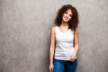 Image of happy young woman standing isolated over gray background. Looking camera pointing