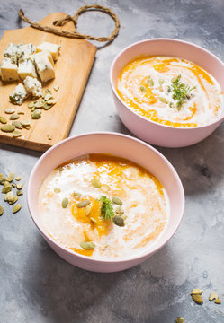 Thick pumpkin soup with feta cheese on concrete background