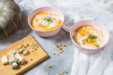 Thick pumpkin soup with feta cheese on concrete background