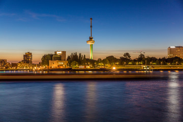 Obraz premium Night cityscape of the New Maas river, the coastal area with lights on and the Euromast tower in the background, quiet night with clear sky in Rotterdam, Netherlands Holland