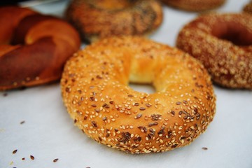 appetizing bagel with sesame seeds close-up on the background of baking on a white background on the counter of a bakery