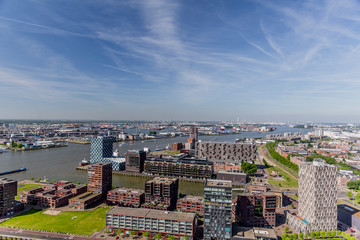 Aerial cityscape of buildings, the Maas river, streets, small green areas with trees and the port in the background in the city of Rotterdam, sunny day with a blue sky, South-Holland, Netherlands
