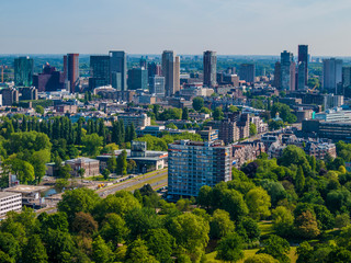 Aerial cityscape of a part of the city of Rotterdam, avenue, buildings, skyscrapers, park and abundant green leafy trees, sunny day with a clear sky in South Holland, Netherlands