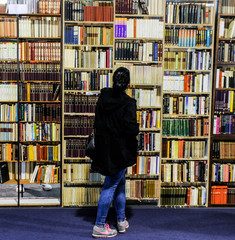 A woman looks at large book shelf