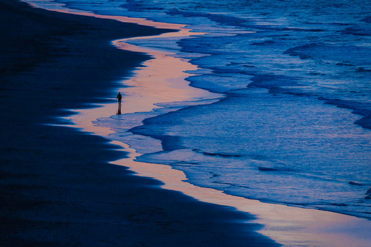 Lone Walker on Beach as tide Rises at Sunset