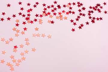 Festive pastel pink background with metallic confetti.