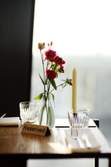 Naklejka na ściany i meble Reserved table in a cafe or restaurant with flowers in a vase and a candle.