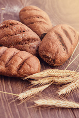 Delicious freshly bakery products and spikelets of wheat on wooden background.