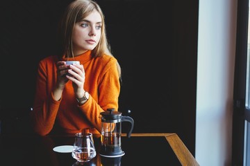 young beautiful woman drinking from a cup in trendy urban cafe