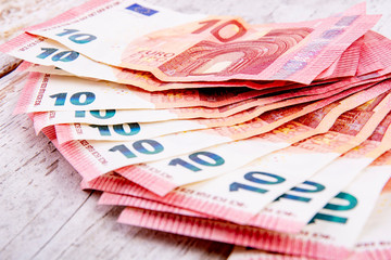 a lot of ten euro bills on white rustic wood