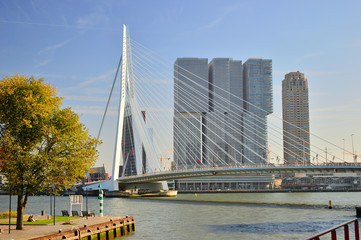 Most wiszący nad rzeką i budynki w słoneczne popołudnie.
