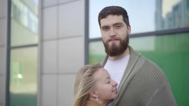 Shot of a short girl hugging tigh her tall boyfriend outdoor, happy smiles on faces.