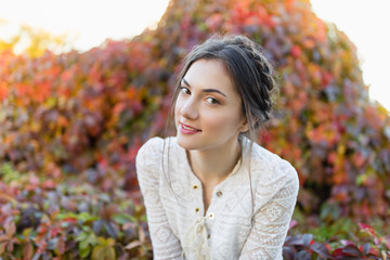 Beautiful girl in a white lace blouse in an autumn park