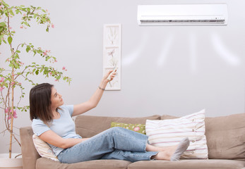 woman using remote control of air conditioner