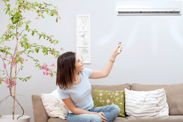 woman using remote control of air conditioner