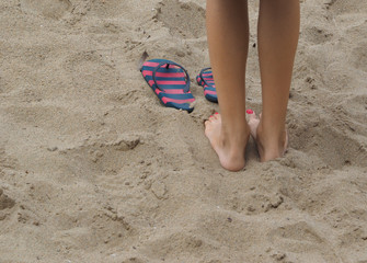 Fototapeta na wymiar Feet girls and slates in the sand