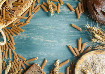 Wholemeal pasta and bread on rustic background
