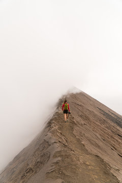 A young woman walking on a ridge near a volcano