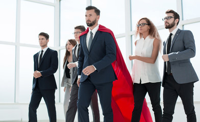 businessman in Superman cloak and business team standing in offi