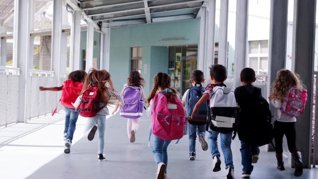 Elementary school kids run from camera in school corridor