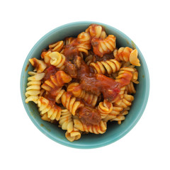 Top view of a bowl of rotini pasta in a sausage and tomato sauce isolated on a white background.