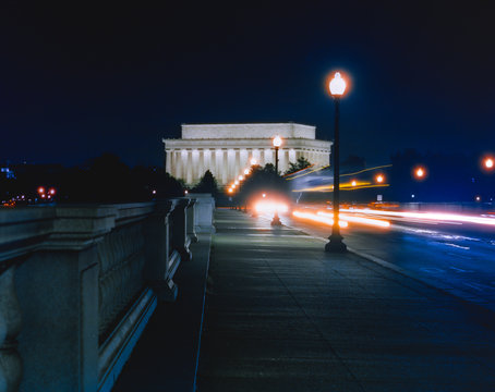 Horizontal view of the Lincoln Memorial with blurred oncoming traffic at night