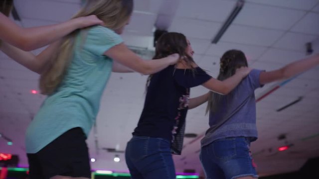 Slow motion shot of girls holding shoulders skating in a row / Orem, Utah, United States