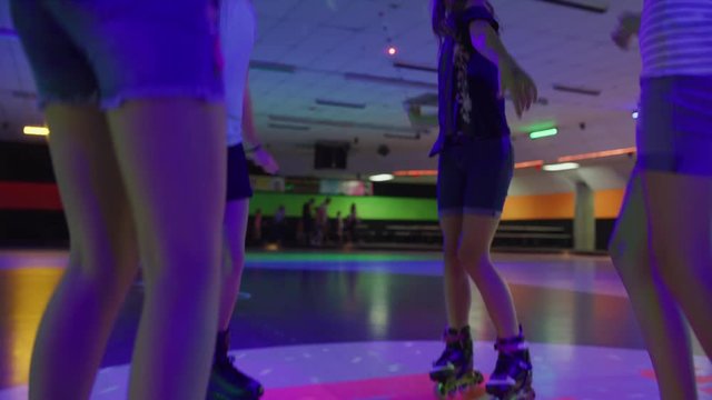 Slow motion shot of girls dancing and singing in circle at roller skating rink / Orem, Utah, United States