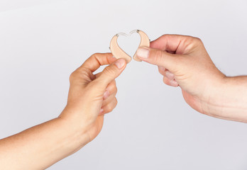 Woman’s and man’s hand forming a heart shape together with hearing aids