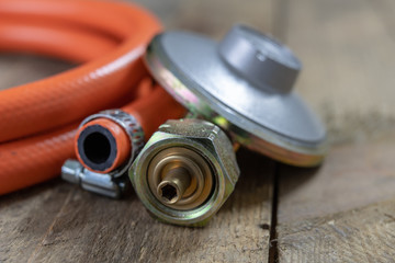 Regulator for propane-butane gas cylinder and accessories on a wooden workshop table. Gas...