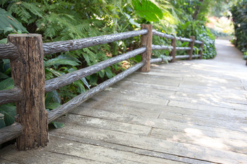 The wooden bridge as a shortcut to the wild.Wooden footbridge ropes in daylight with forest background.wooden fence with dirt road in background.