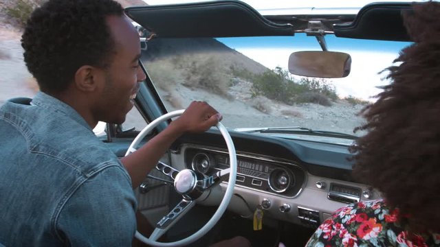 Young black couple in convertible dancing in their seats