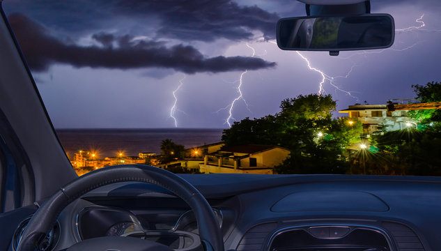 Car Windshield With View Of Lightning Storm Over The Sea