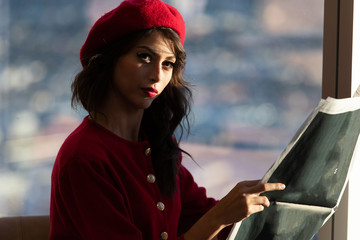 Obraz premium Woman dressed in red fashion reading a newspaper