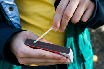 Tourist lights the fire with a matchbox of matches. Concept of safety of children from the threat of fire and parental supervision of explosive substances. Close up