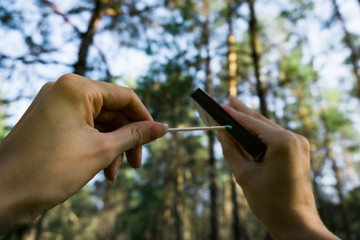 Close-up of hands that hold matches to make a fire. The concept of danger and the rules of fire use in forests