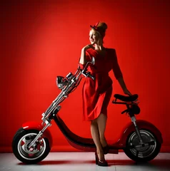 Foto op Plexiglas Woman ride new electric car motorcycle bicycle scooter present for new year 2019 in red dress on red background  © Dmitry Lobanov