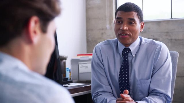 Mixed race manager speaking to young man at job interview