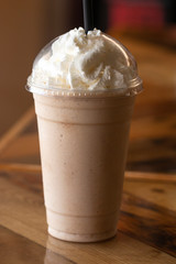 Cold Frappa with Whipped Cream on a Wooden Table in a Cafe