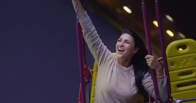 Portrait of a beautiful young woman (girl) having fun on the rides at the Luna Park. Concept: Happiness, freedom, fun.