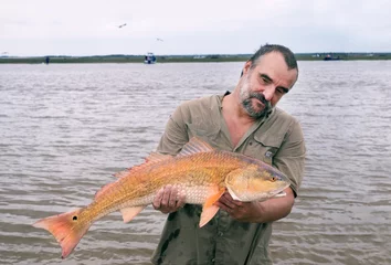 Zelfklevend Fotobehang Fisherman with a big catch - golden fish Red drum (Sciaenops ocellatus). Texas Gulf Coast, USA © Irina K.