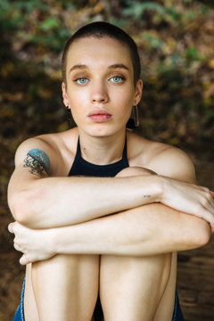 Woman with crewcut sitting and hugging her knees