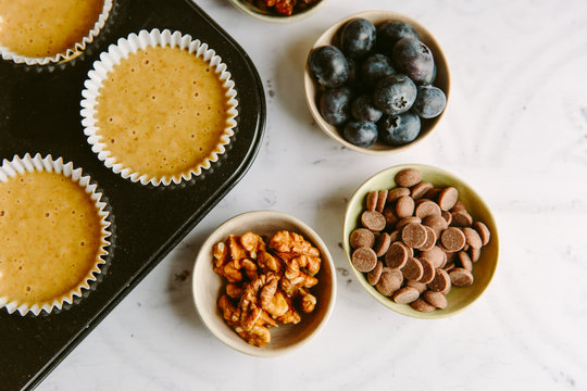 Uncooked plain muffin batter with various flavouring additions - blueberries, walnuts, chocolate, raisins.